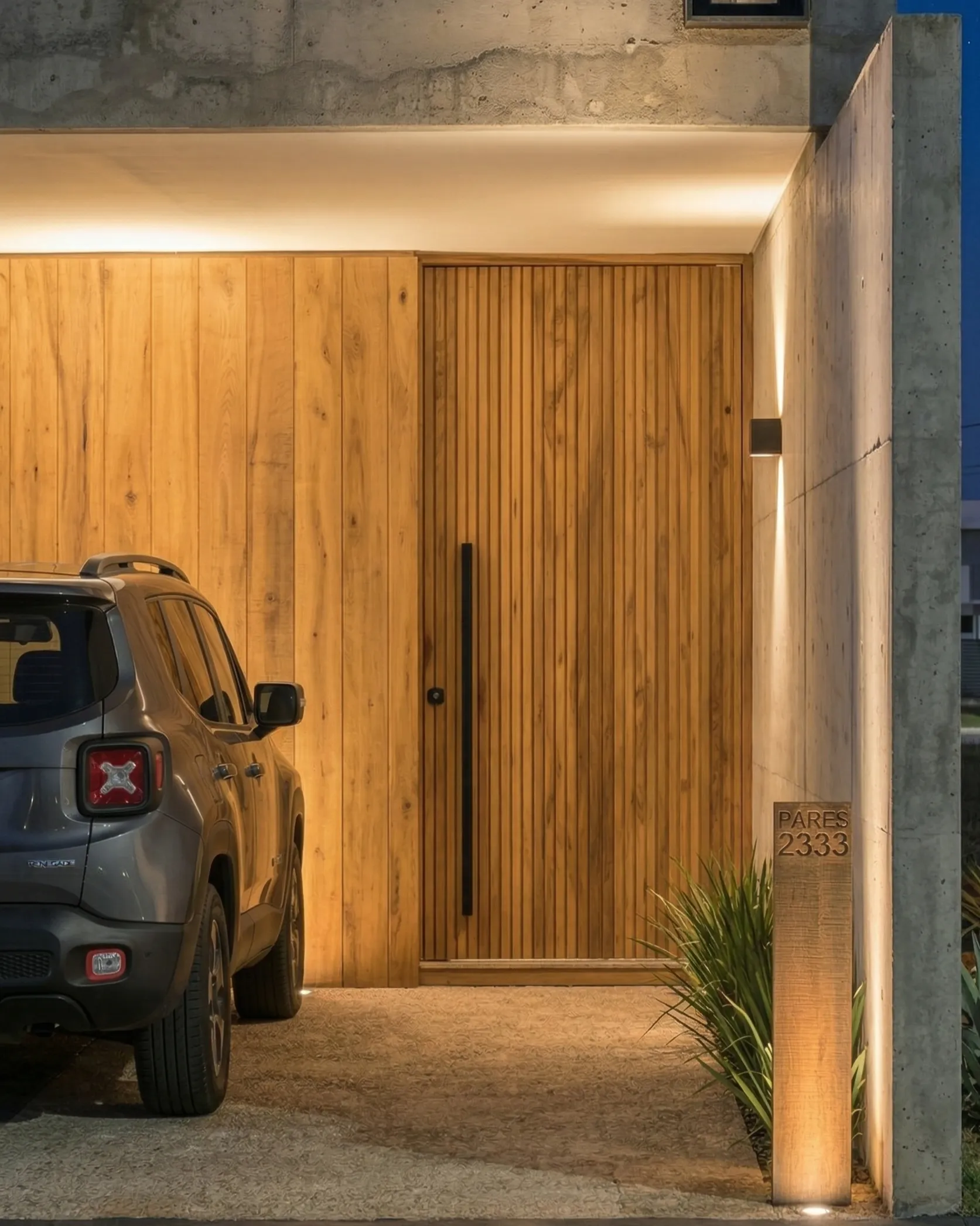 Cocina moderna con gran isla central de concreto pulido y carpintería de madera de nogal